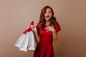a woman in a red dress holding shopping bags