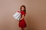 a woman in a red dress holding shopping bags
