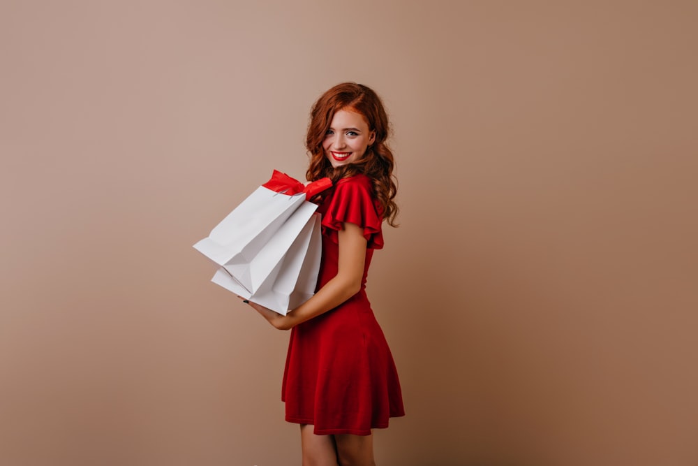 a woman in a red dress holding shopping bags