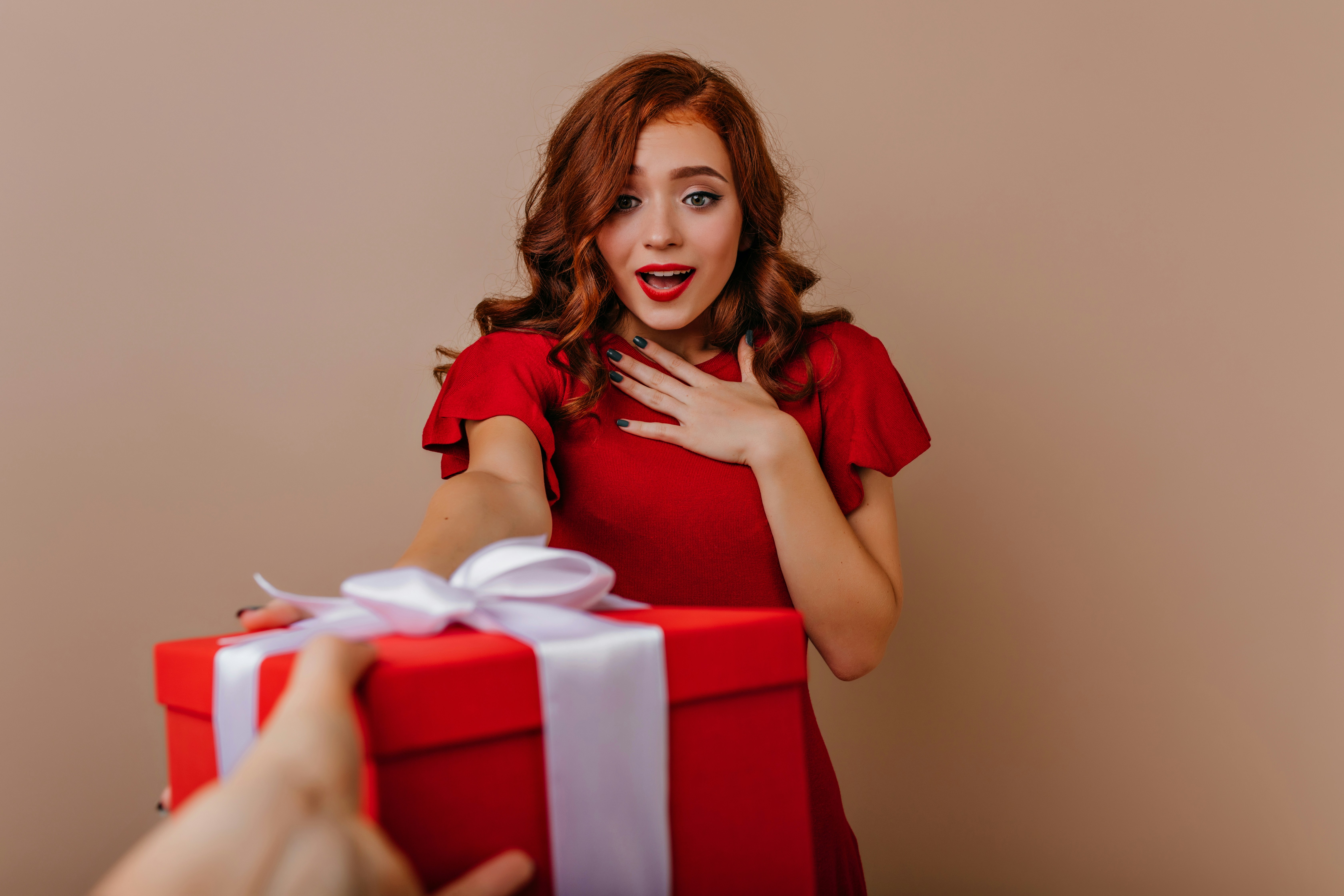 A woman in a red dress holding a red gift box