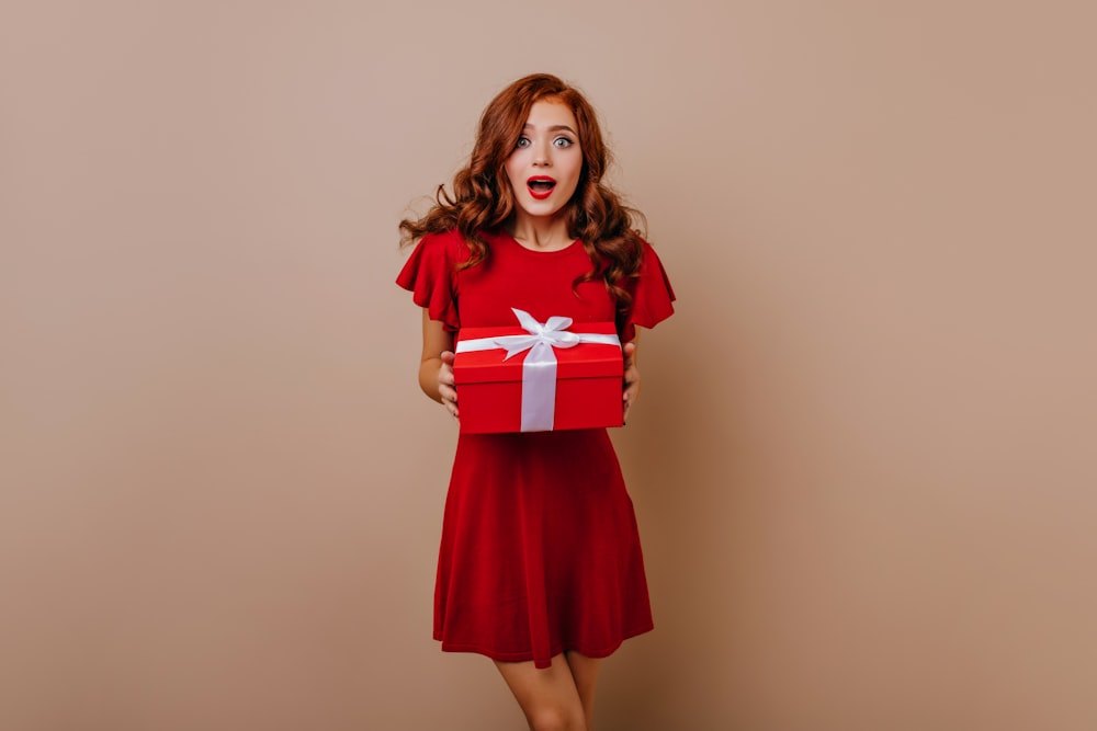 a woman in a red dress holding a red gift box