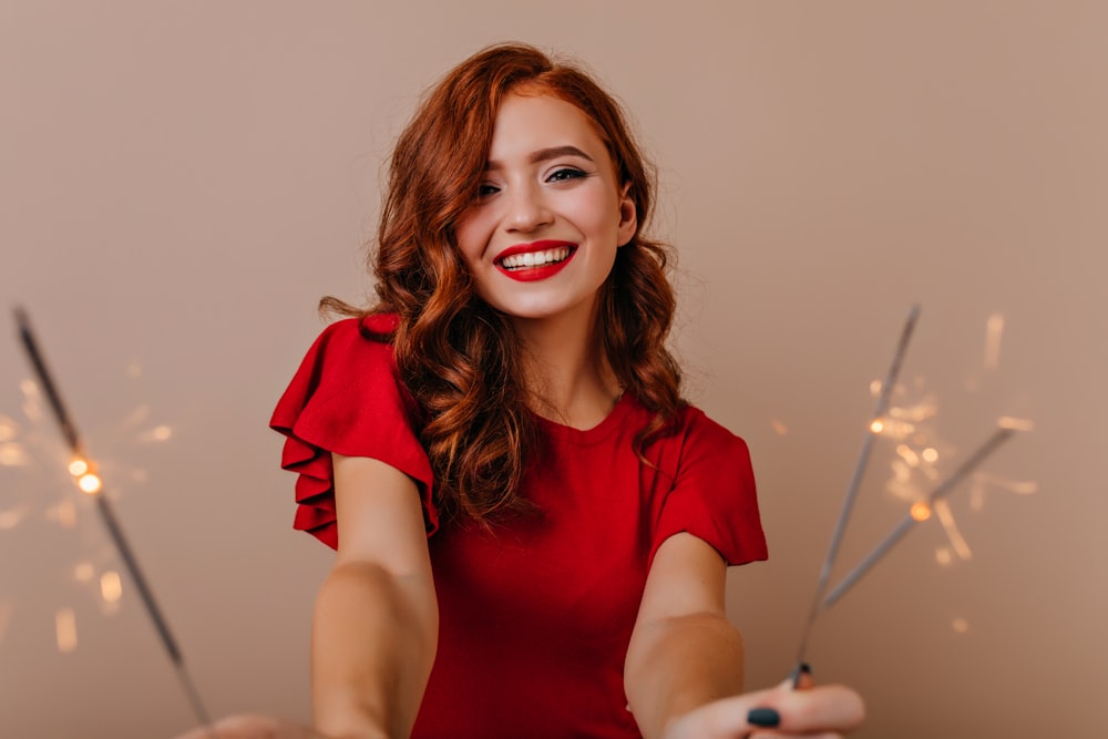 a woman in a red dress is holding sparklers