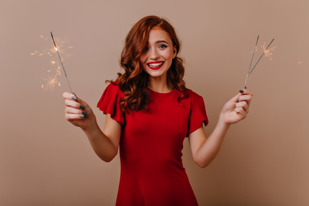 a woman in a red dress holding two sparklers