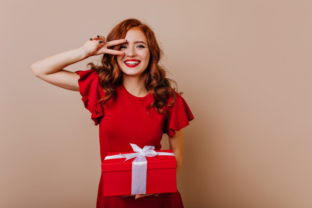 a woman in a red dress holding a red gift box