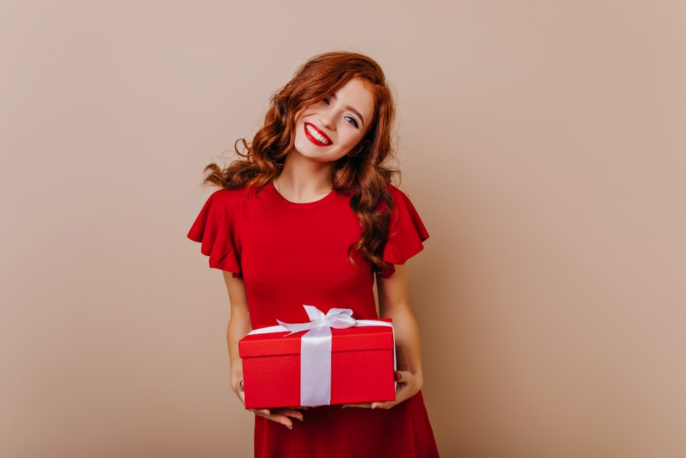 a woman in a red dress holding a red gift box