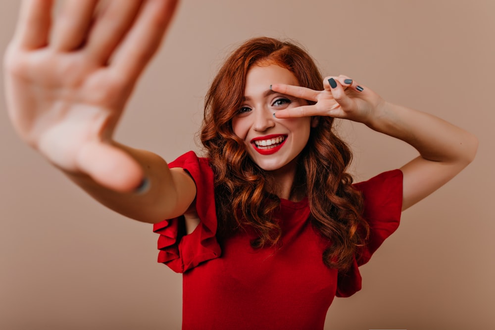 a woman in a red shirt is holding her hands up