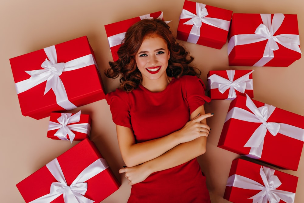 a woman in a red dress surrounded by red and white wrapped presents