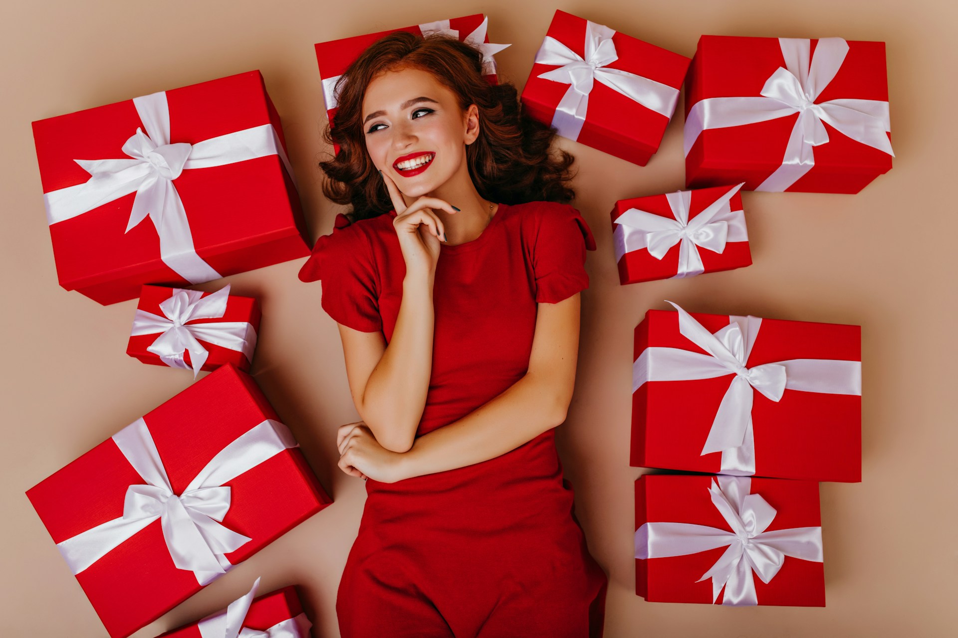 a woman in a red dress surrounded by red and white wrapped presents