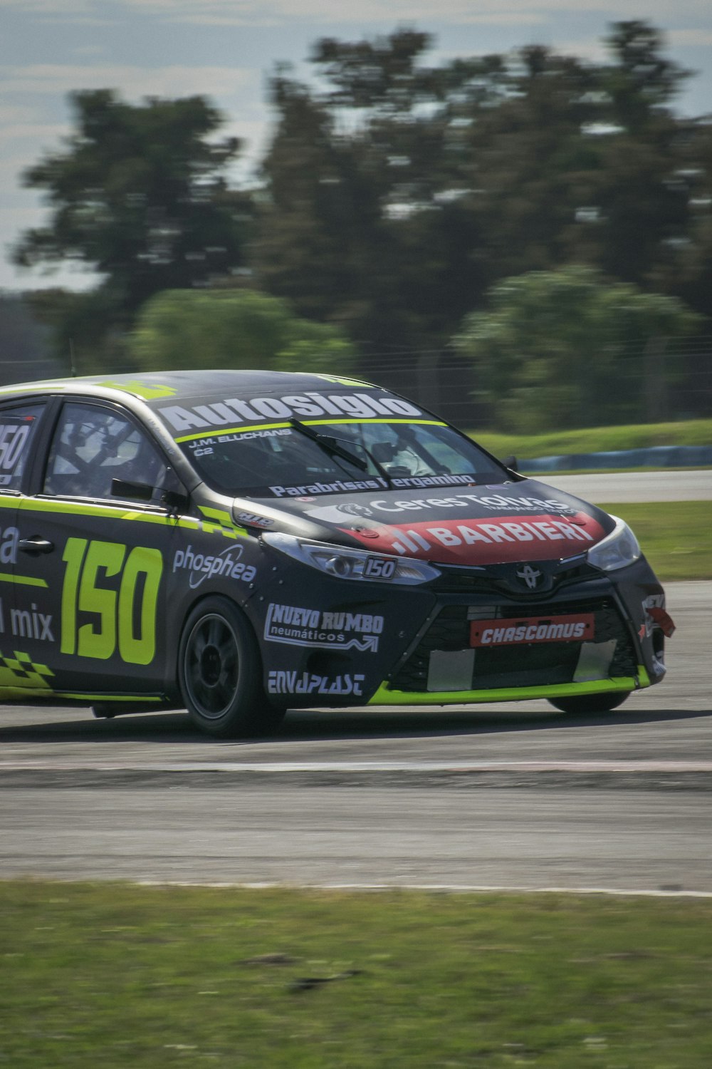 a car driving on a race track with trees in the background