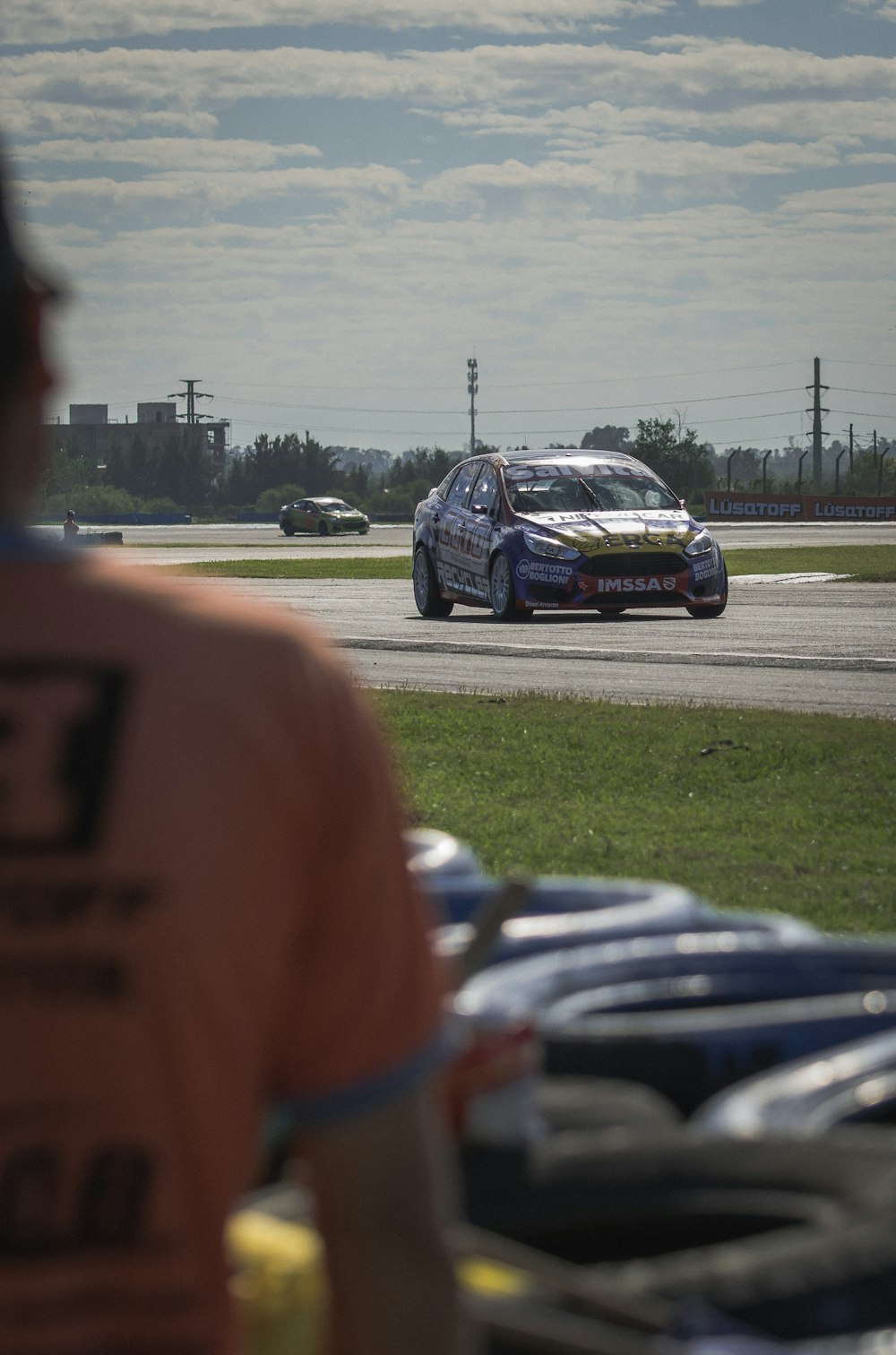 a car driving on a race track with other cars behind it