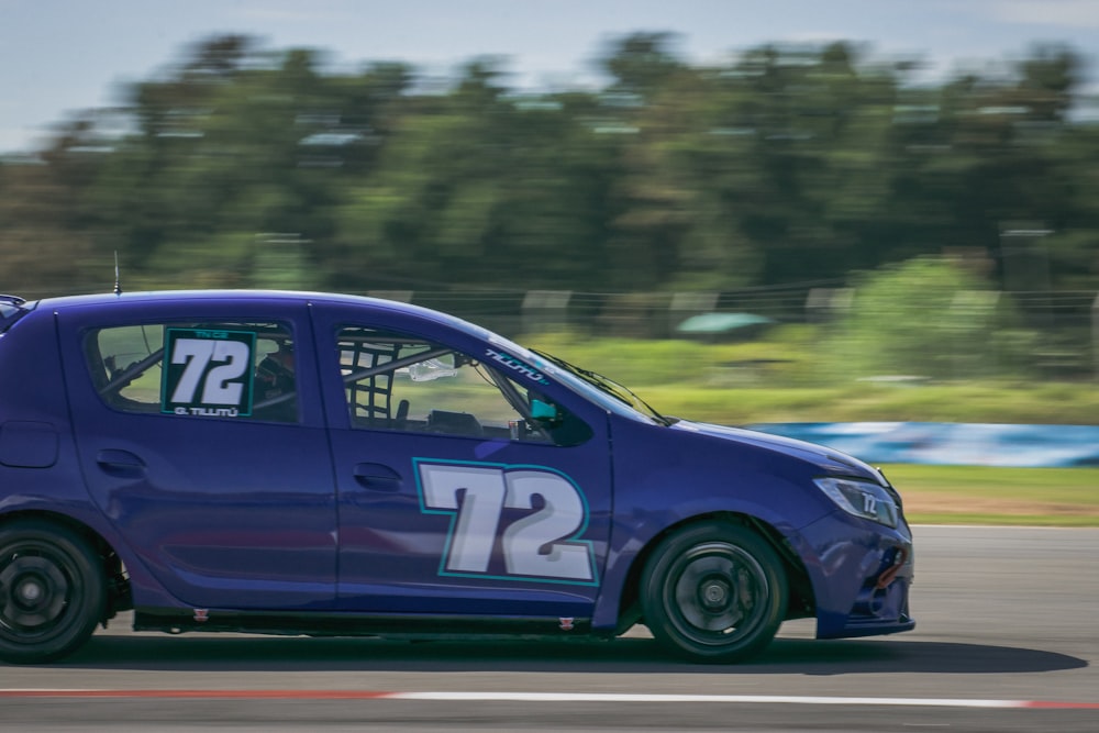 a small blue car driving down a race track