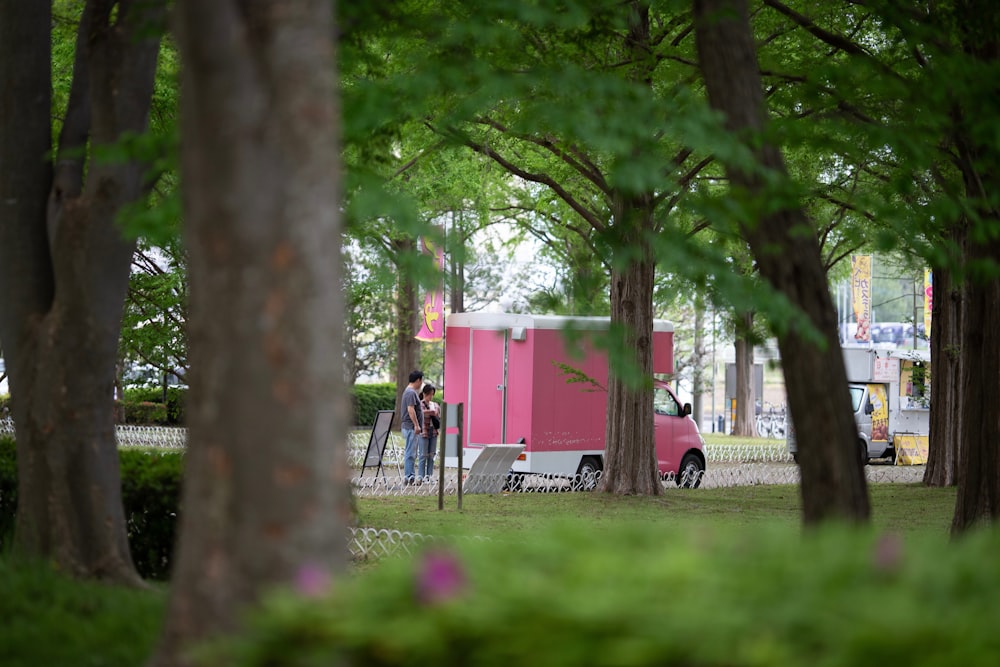 a pink food truck parked in the middle of a park