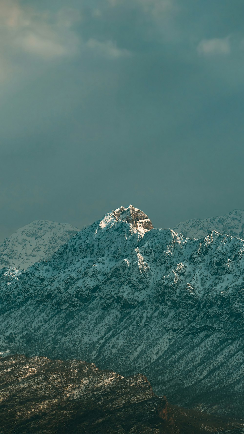 a snow covered mountain range under a cloudy sky