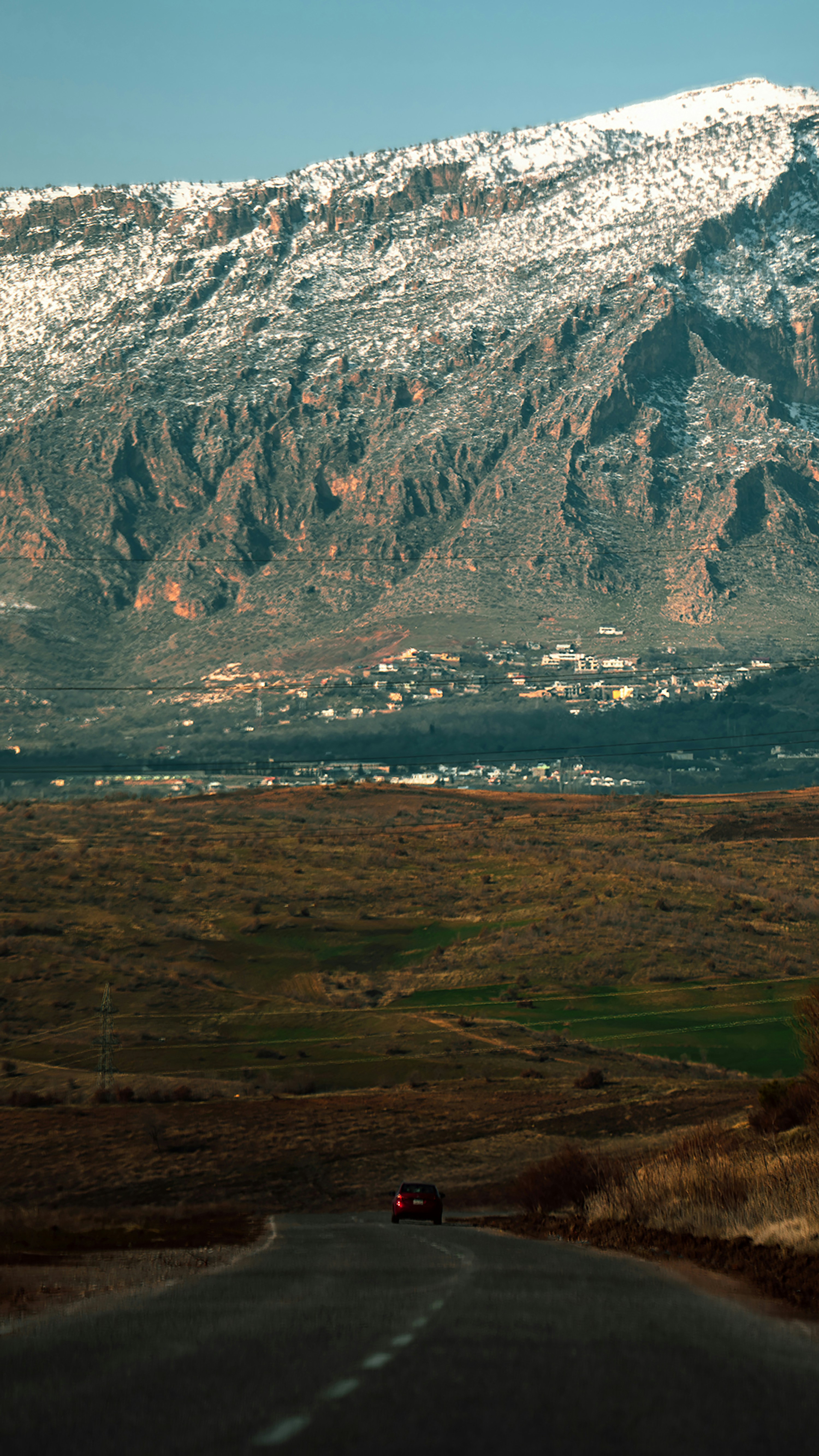 a car driving down a road with a mountain in the background