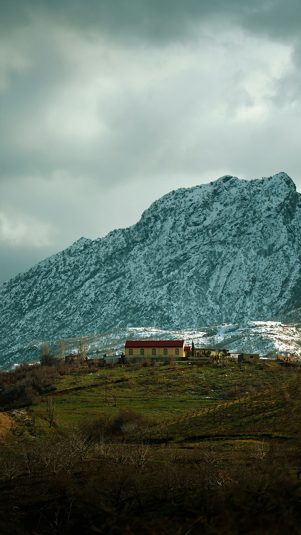 a large snow covered mountain with a house in the foreground