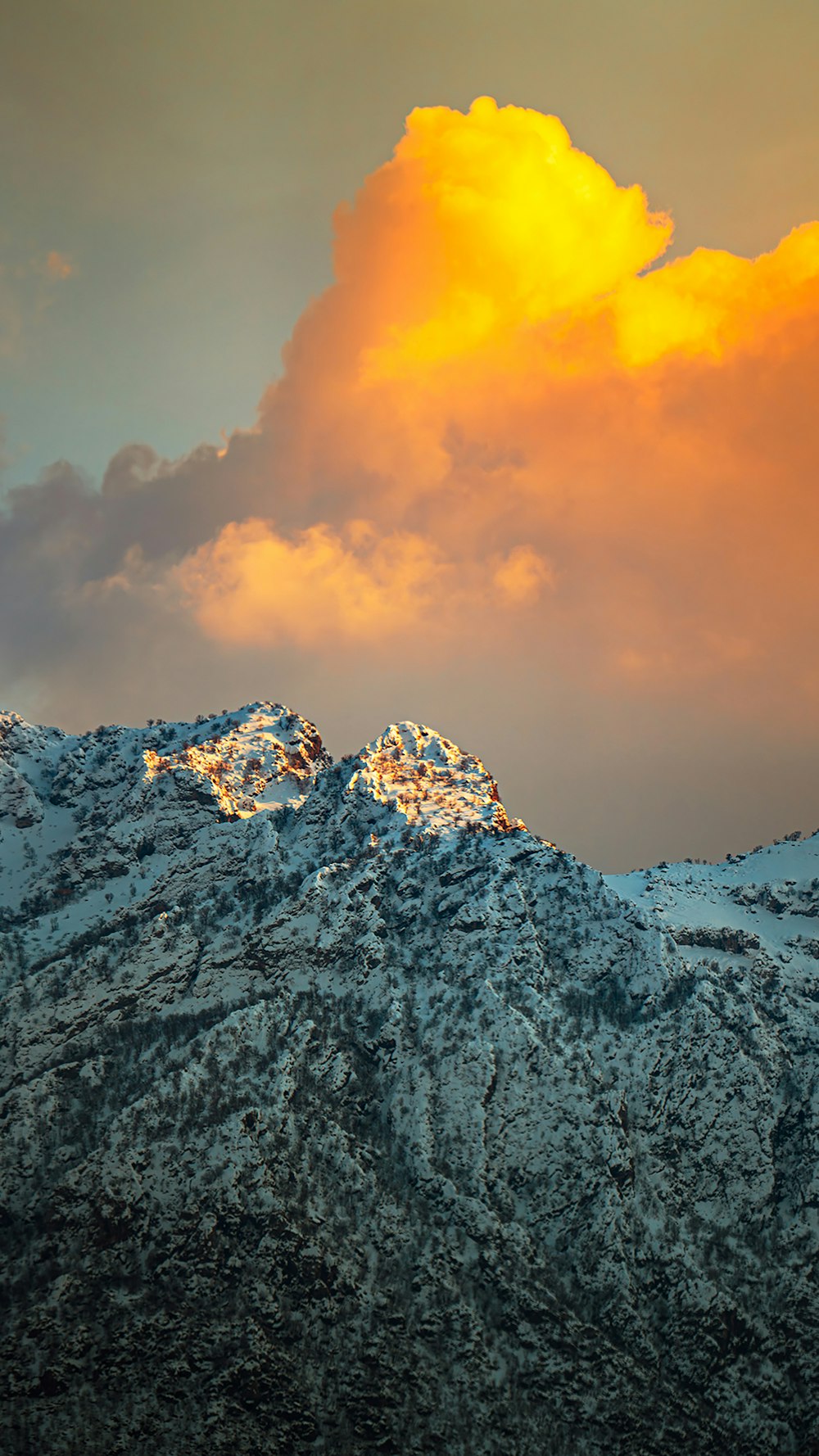 a mountain covered in snow under a cloudy sky