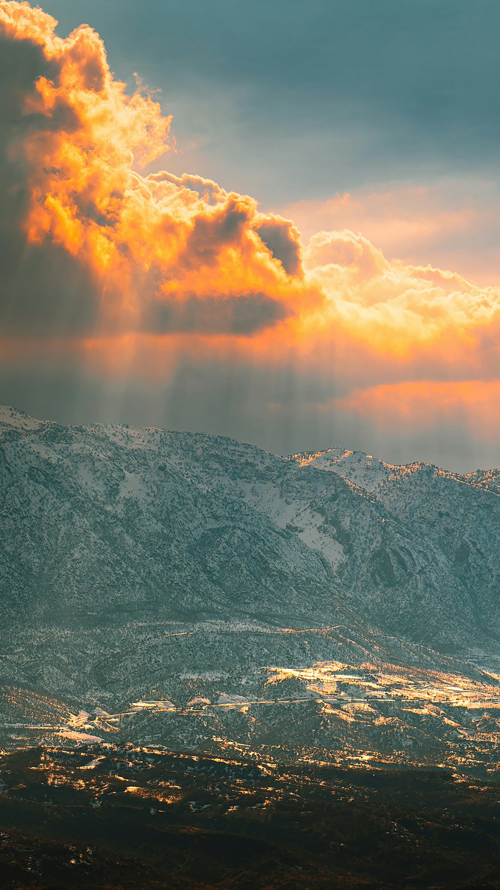 a plane flying over a mountain range under a cloudy sky