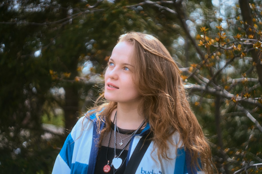 a young girl standing in front of a tree