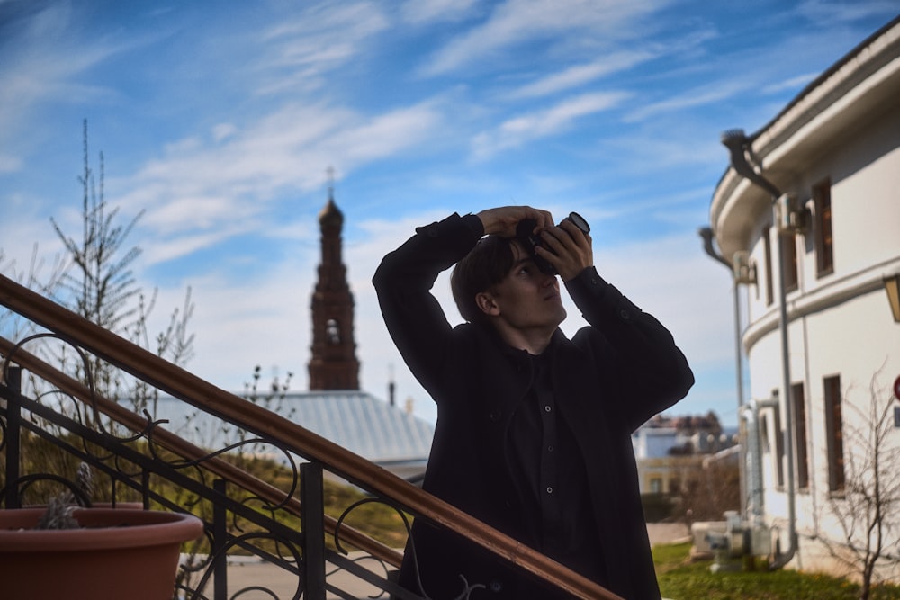 a man standing on the steps of a building looking through a pair of binoculars