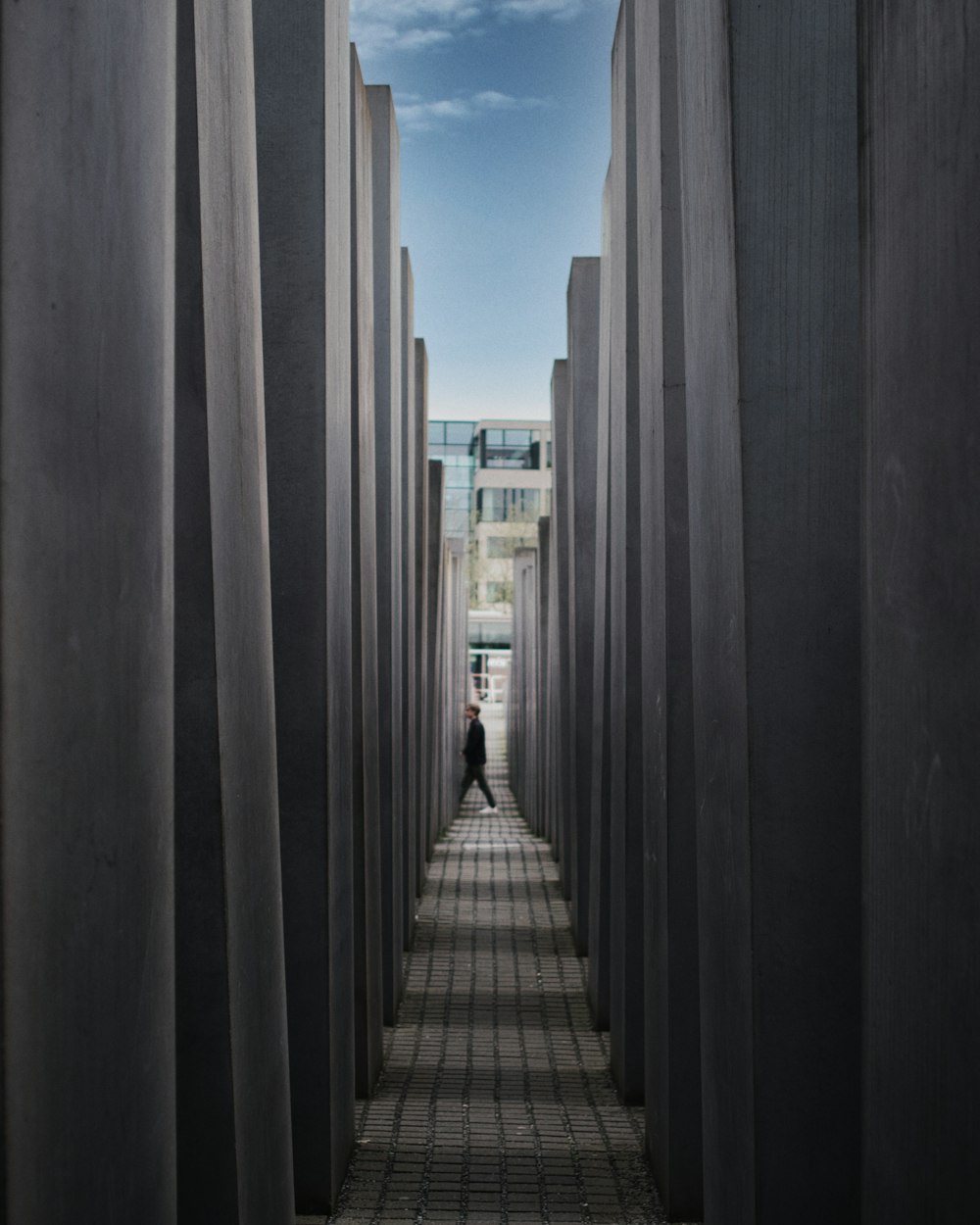 a man walking through a tunnel of cement pillars