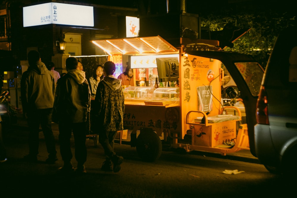 a group of people standing around a food cart