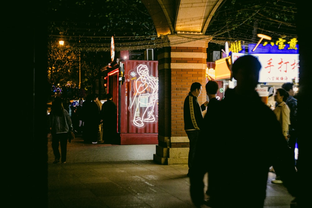 a group of people walking down a street at night