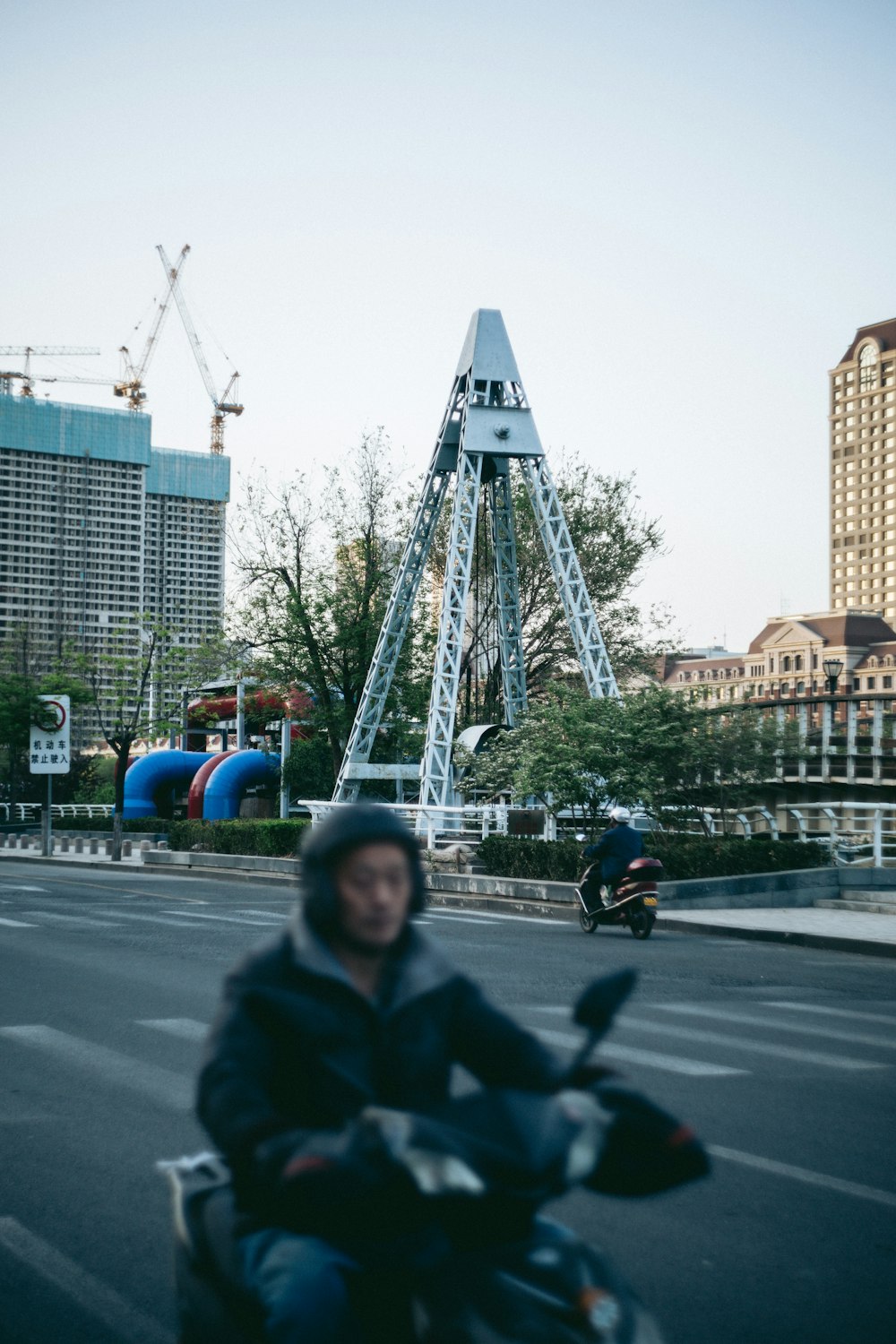 a man riding a motorcycle down a street next to tall buildings