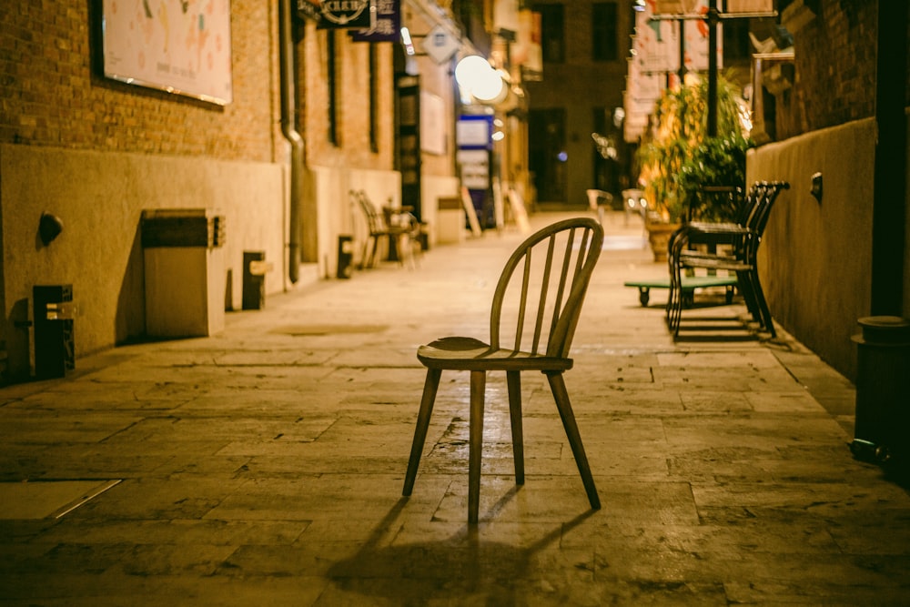 a wooden chair sitting on the side of a street