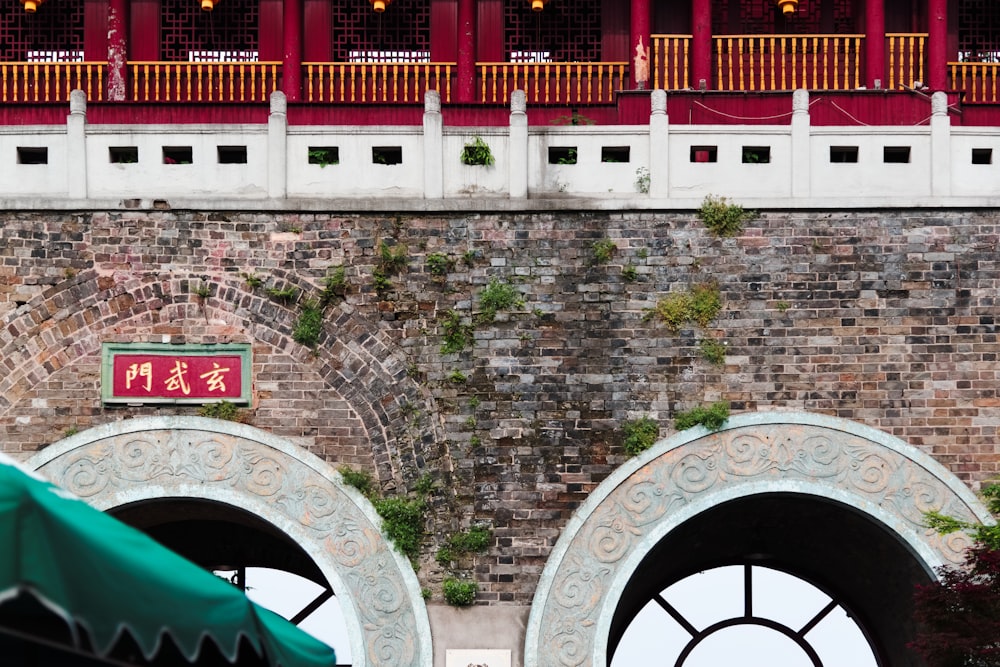 a brick wall with two archways and a green umbrella