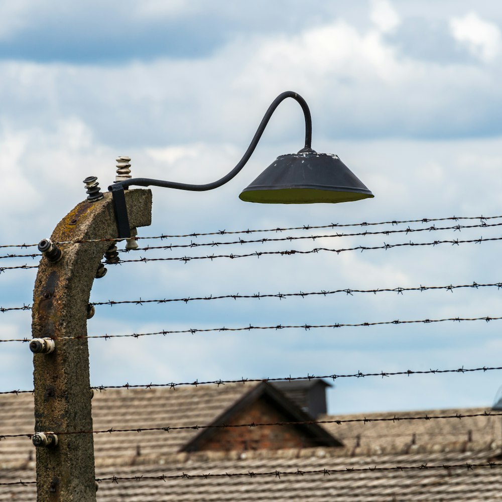 a lamp on a pole next to a barbed wire fence
