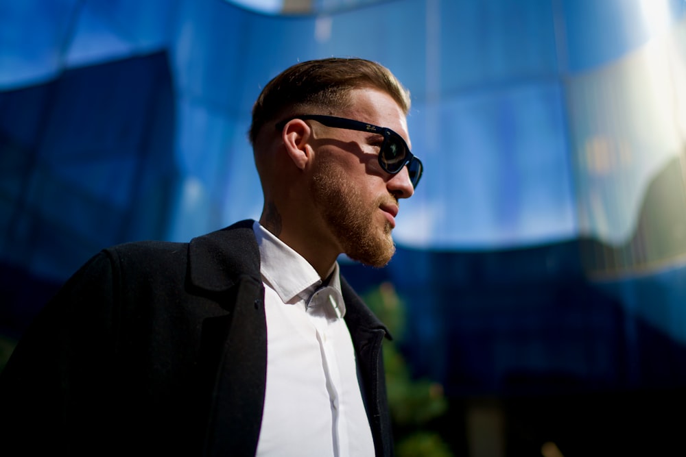 a man wearing a suit and sunglasses in front of a building