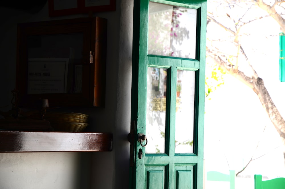 una porta verde in una stanza con un albero sullo sfondo