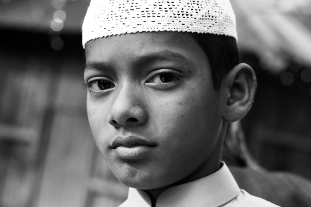 a black and white photo of a young boy wearing a hat