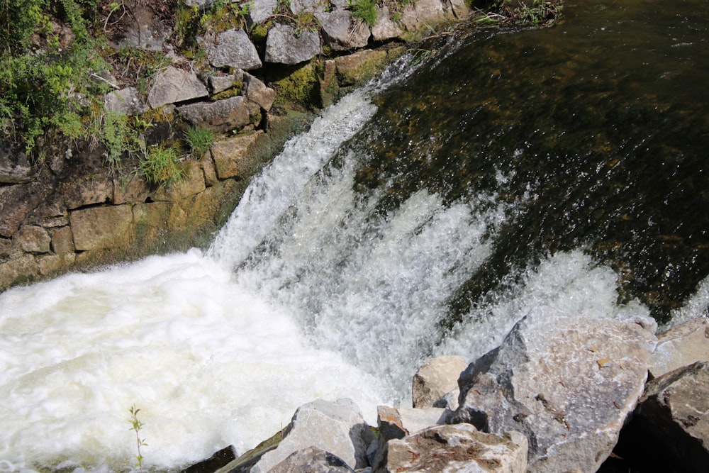 a man standing on a rock next to a waterfall