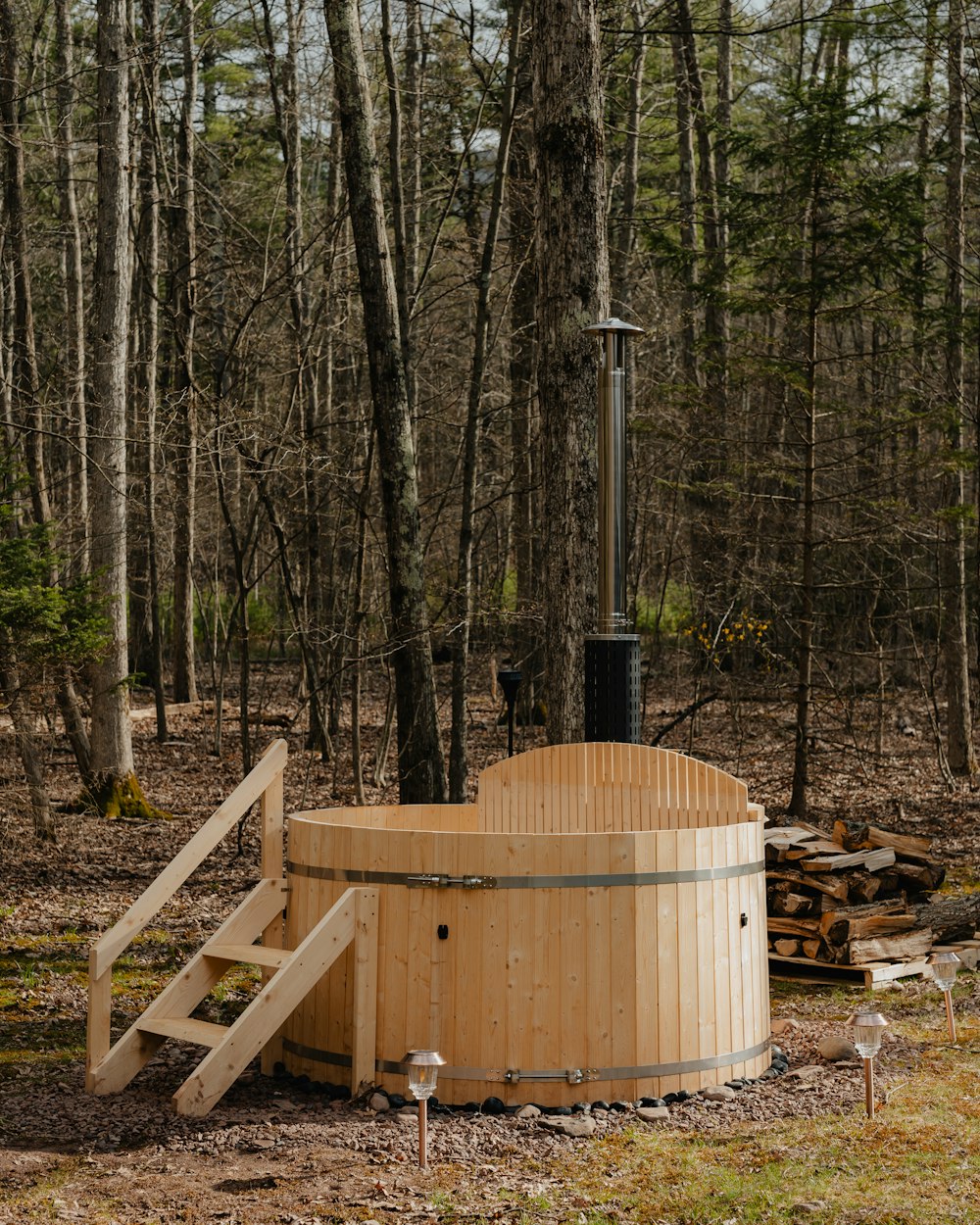 a wooden hot tub in the middle of a forest