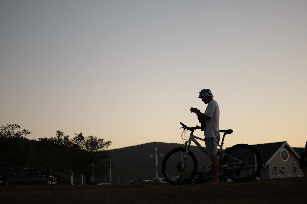 a man standing next to a bike in a field