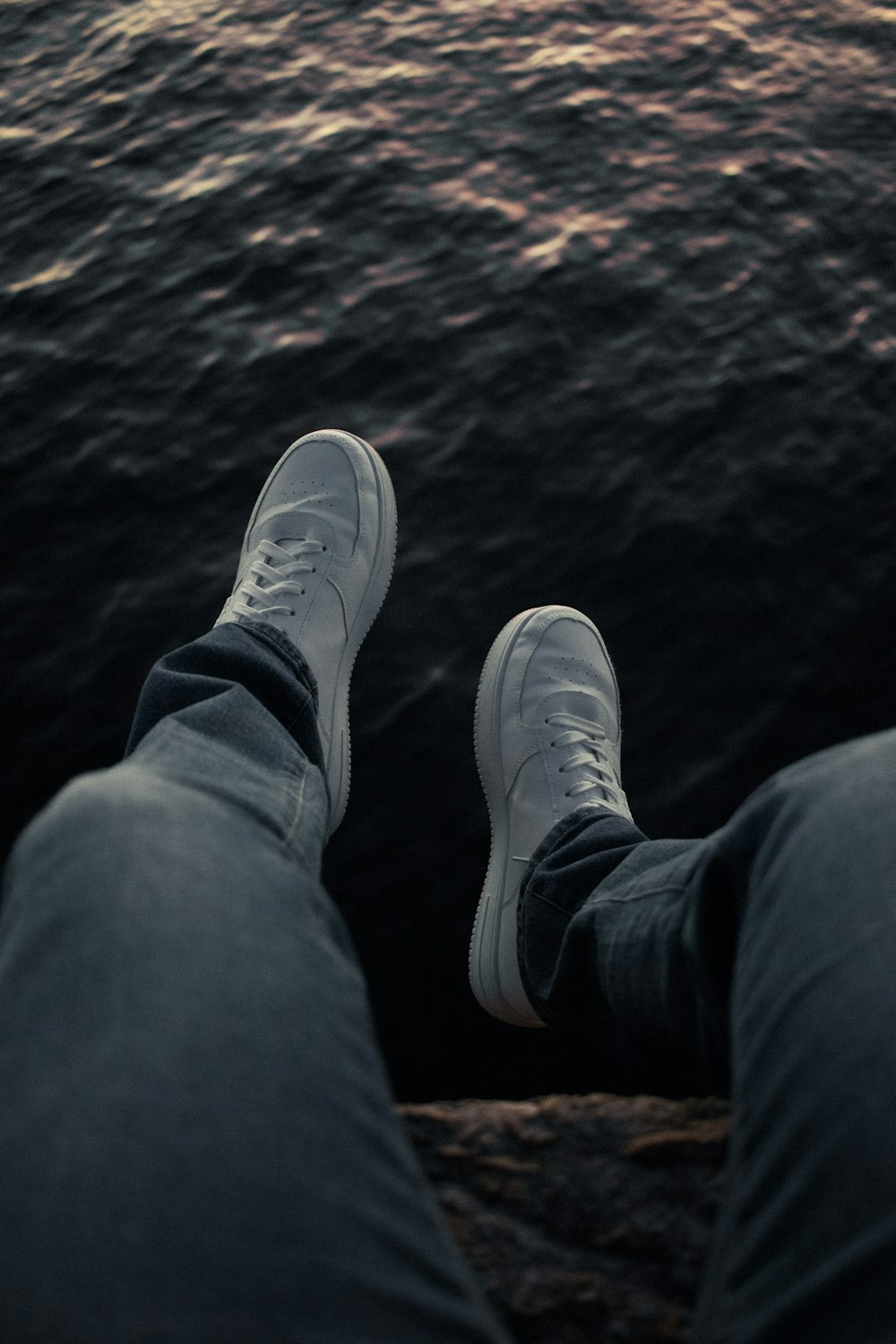 a person standing on the edge of a pier next to a body of water