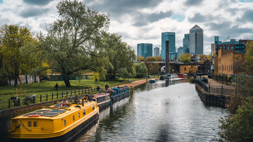 a yellow boat traveling down a river next to a lush green park