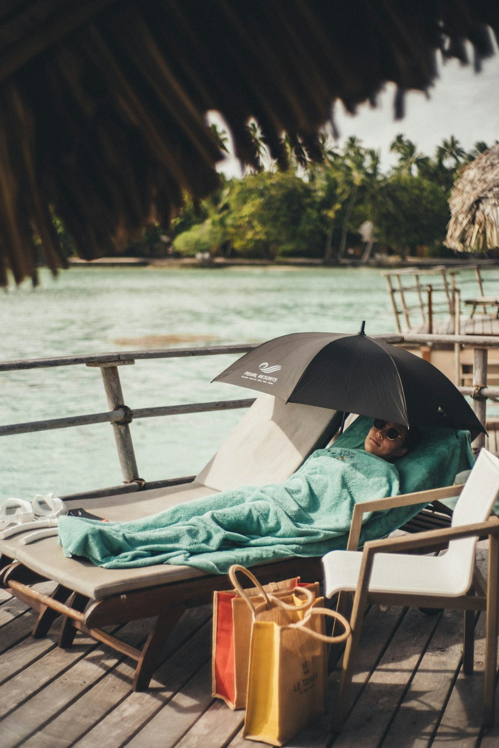a person laying on a deck with an umbrella