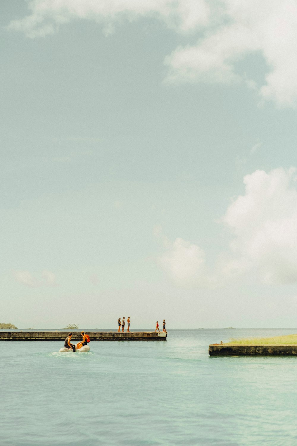 a group of people standing on a pier next to the ocean