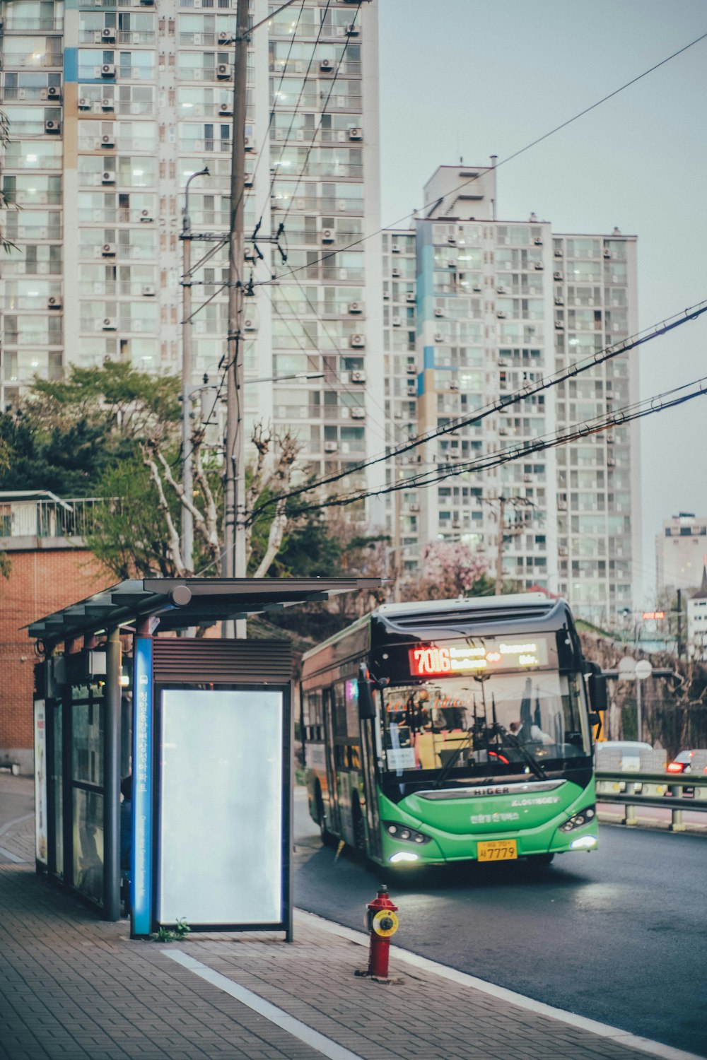 a green bus driving down a street next to tall buildings