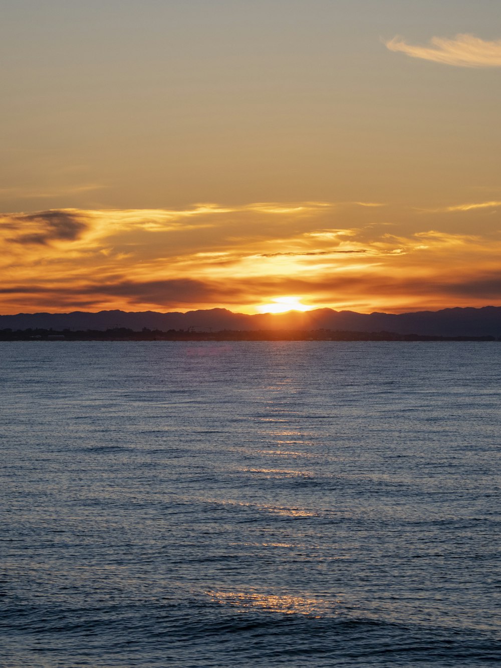 a large body of water with a sunset in the background