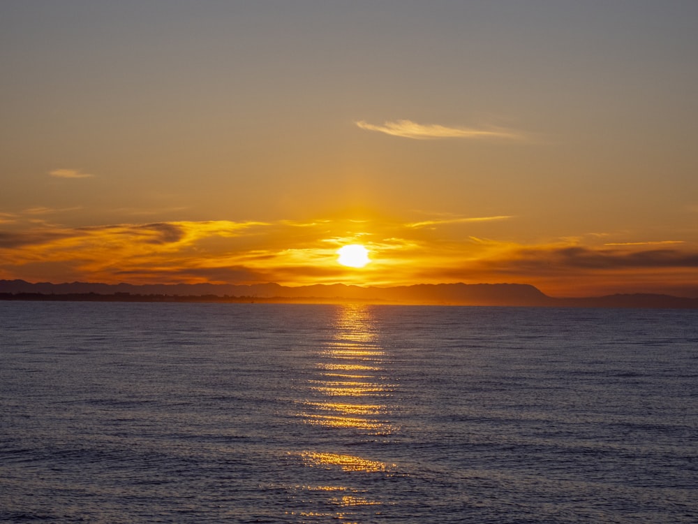 a large body of water with a sunset in the background