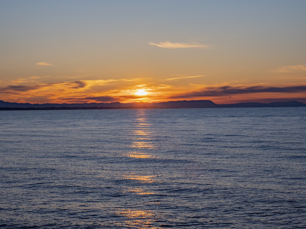 a large body of water with a sunset in the background