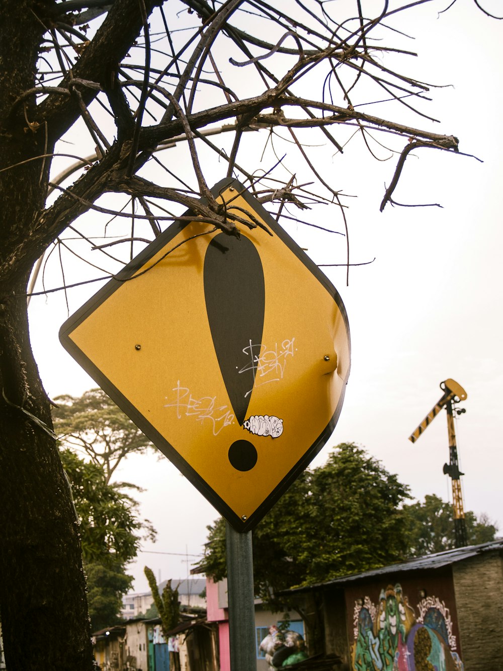 a yellow and black street sign sitting next to a tree