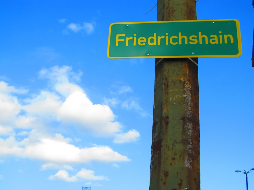 a green street sign hanging from a metal pole