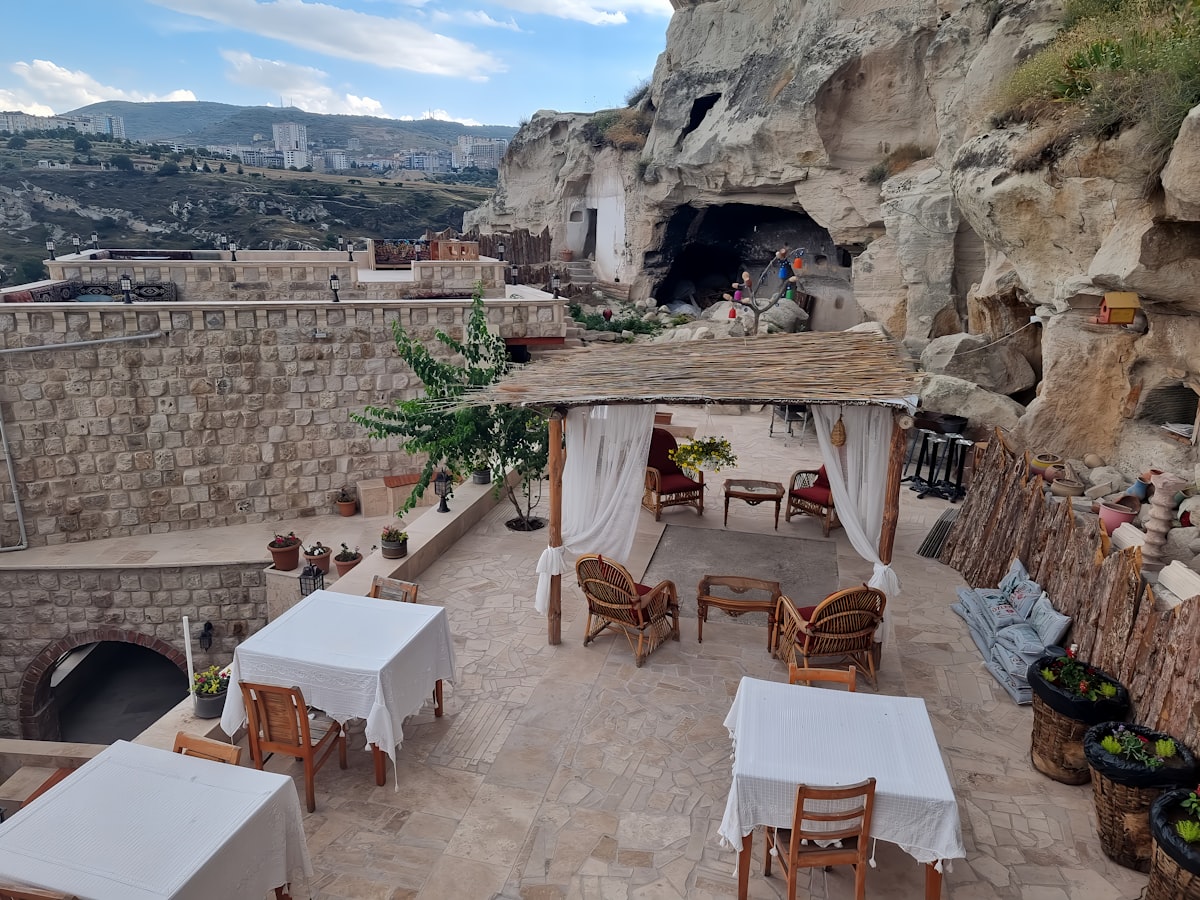 Ürgüp Cappadocia — cave hotel terrace carved into volcanic rock with outdoor dining tables and valley views