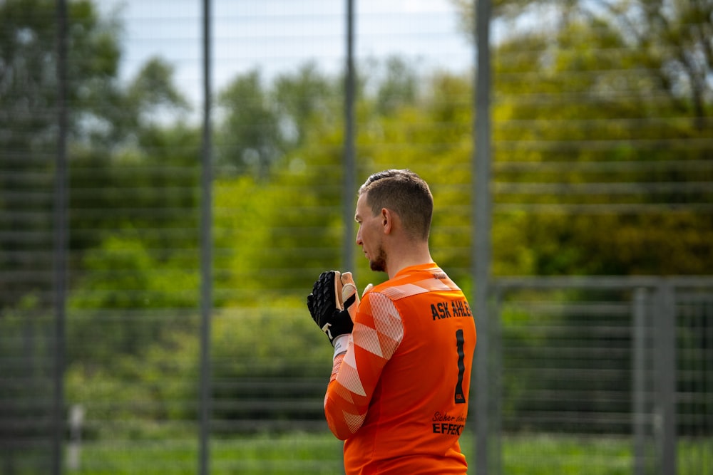 a man in an orange shirt holding a baseball glove