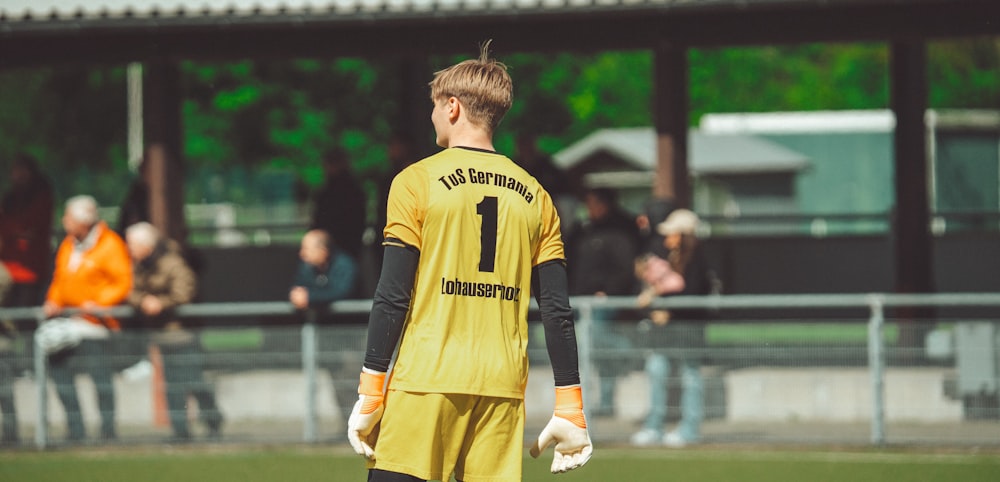 a soccer player in a yellow uniform standing on a field