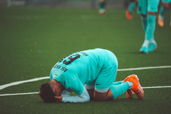a soccer player with his head down on the ground